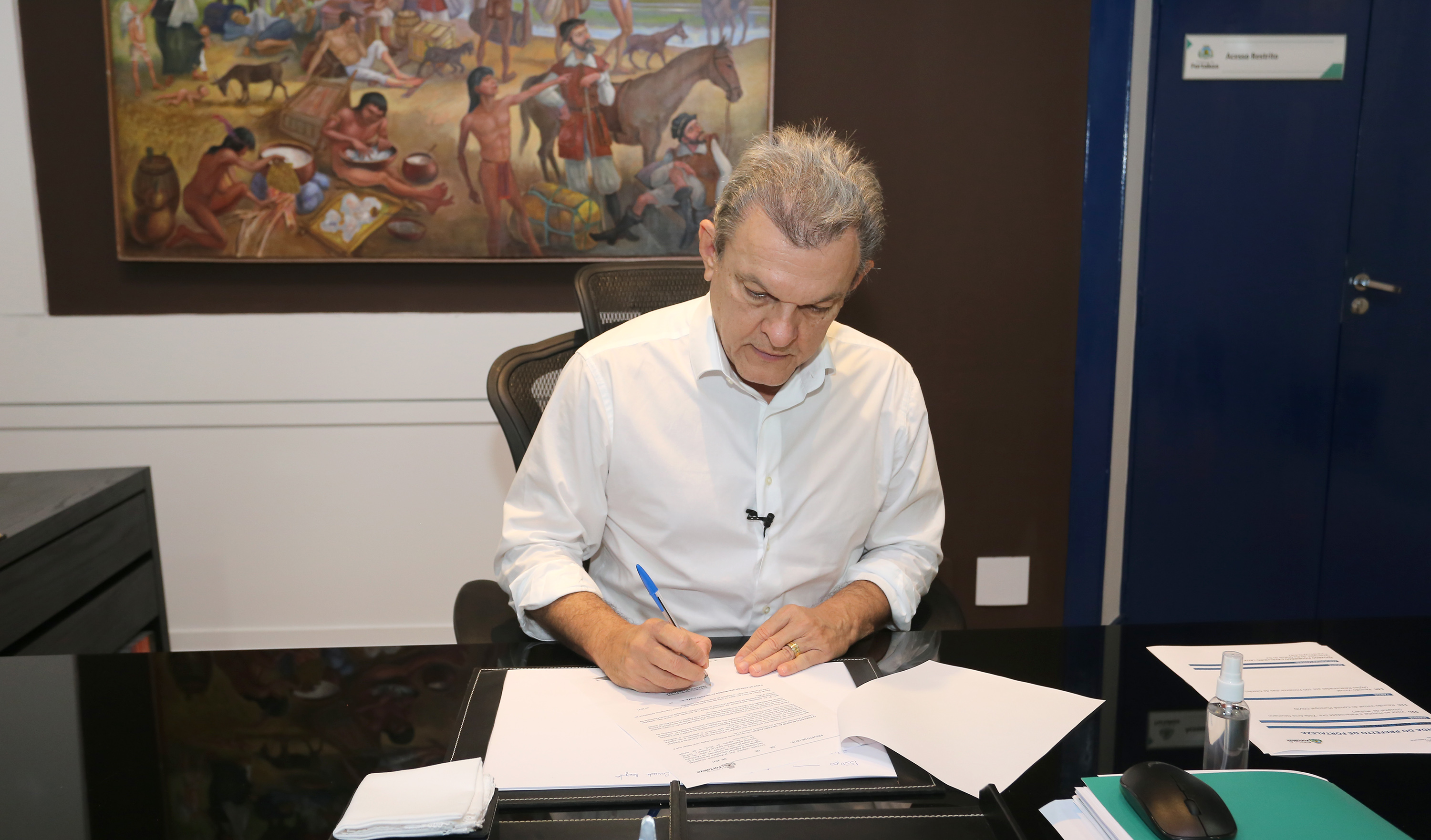 prefeito sarto assina um documento em sua mesa de trabalho no gabinete